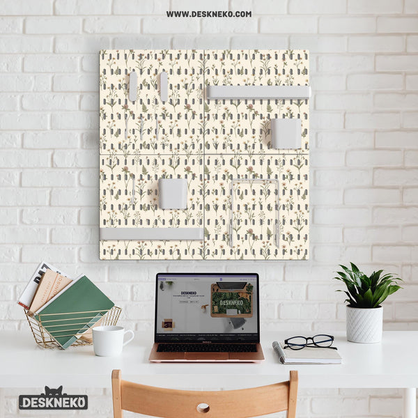Cream pegboard wall organizer with small floral print, sage green stems, black slot layout, shelves, hooks, clips, and containers.