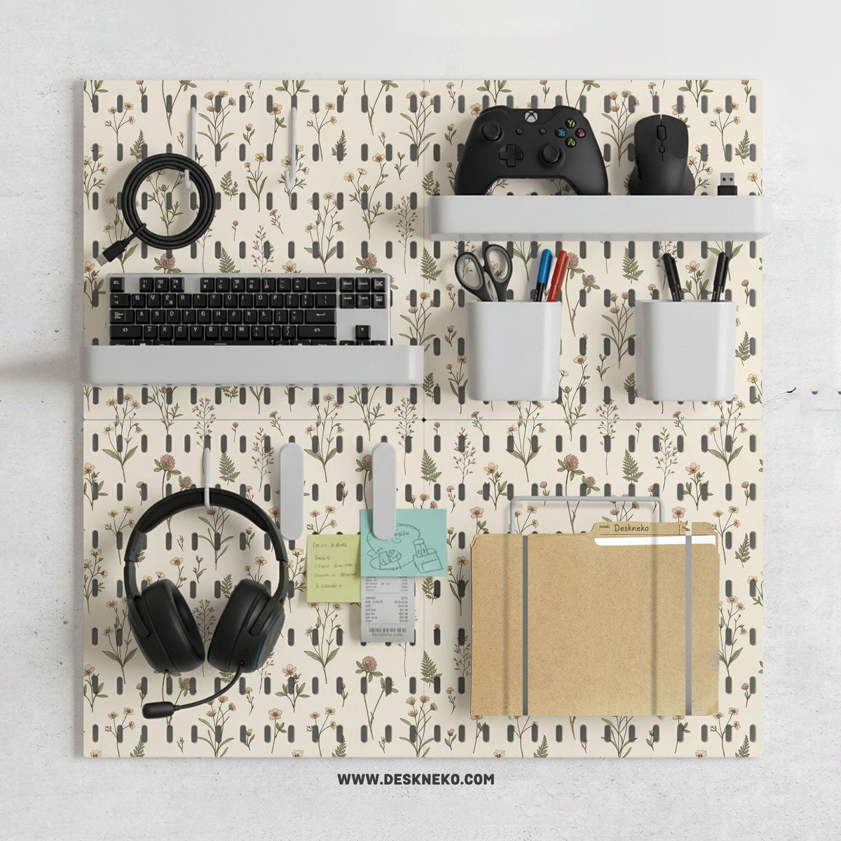 Cream pegboard wall organizer with small floral print, sage green stems, black slot layout, shelves, hooks, clips, and containers.