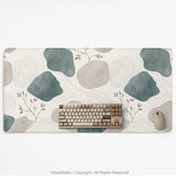 A desk mat with sage green abstract blocks, cream space, gray stone-like shapes, fine topographic contour lines, and small branch details.