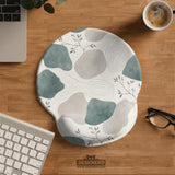 Sage green ergonomic mousepad and keyboard wrist rest with abstract shapes, soft gray details, cream space, topographic contour lines, and leafy branch accents.