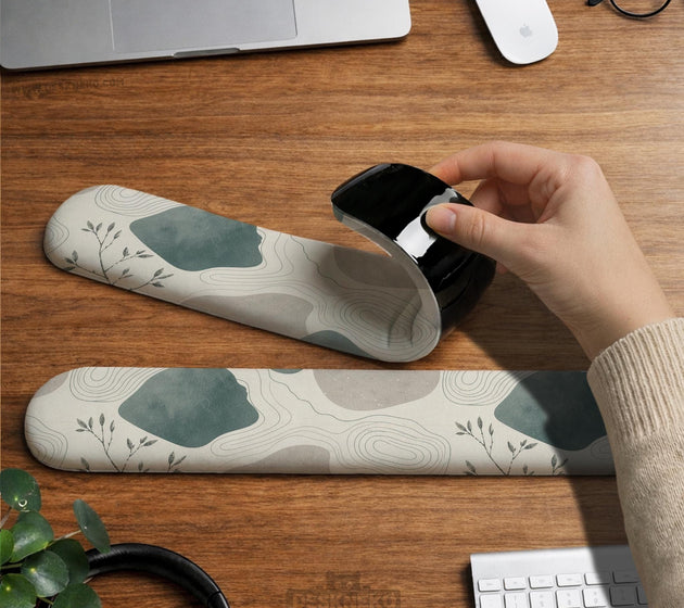 Sage green ergonomic mousepad and keyboard wrist rest with abstract shapes, soft gray details, cream space, topographic contour lines, and leafy branch accents.