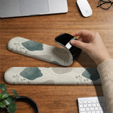 Sage green ergonomic mousepad and keyboard wrist rest with abstract shapes, soft gray details, cream space, topographic contour lines, and leafy branch accents.
