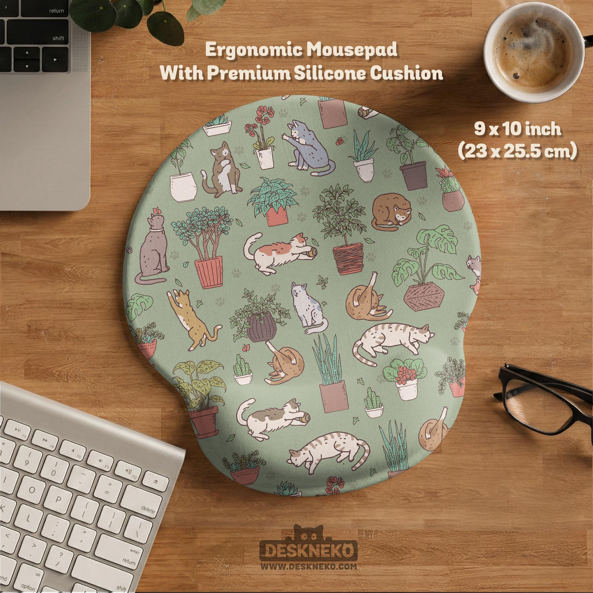 Sage green desk mat with a pattern of lounging cats, leafy plants, cactus pots, and earthy botanical details.