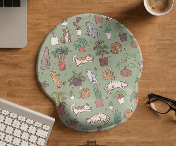 Sage green desk mat with a pattern of lounging cats, leafy plants, cactus pots, and earthy botanical details.