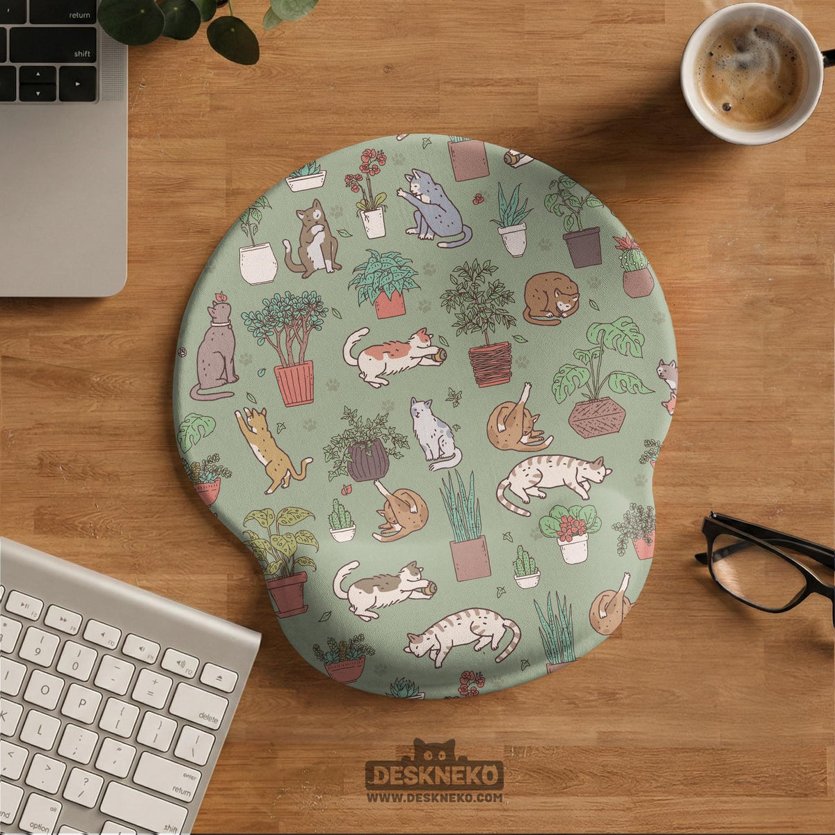 Sage green desk mat with a pattern of lounging cats, leafy plants, cactus pots, and earthy botanical details.