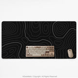 Black desk mat with a thin gray topographic contour line pattern.