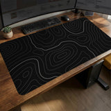 Black desk mat with a thin gray topographic contour line pattern.