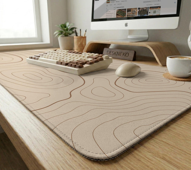 Beige desk mat with soft brown topographic contour lines on a neutral background.