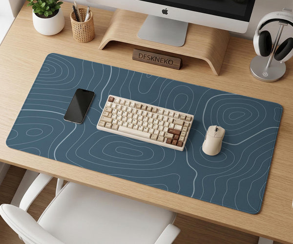 A slate blue desk mat with thin contour line map art on a light background.