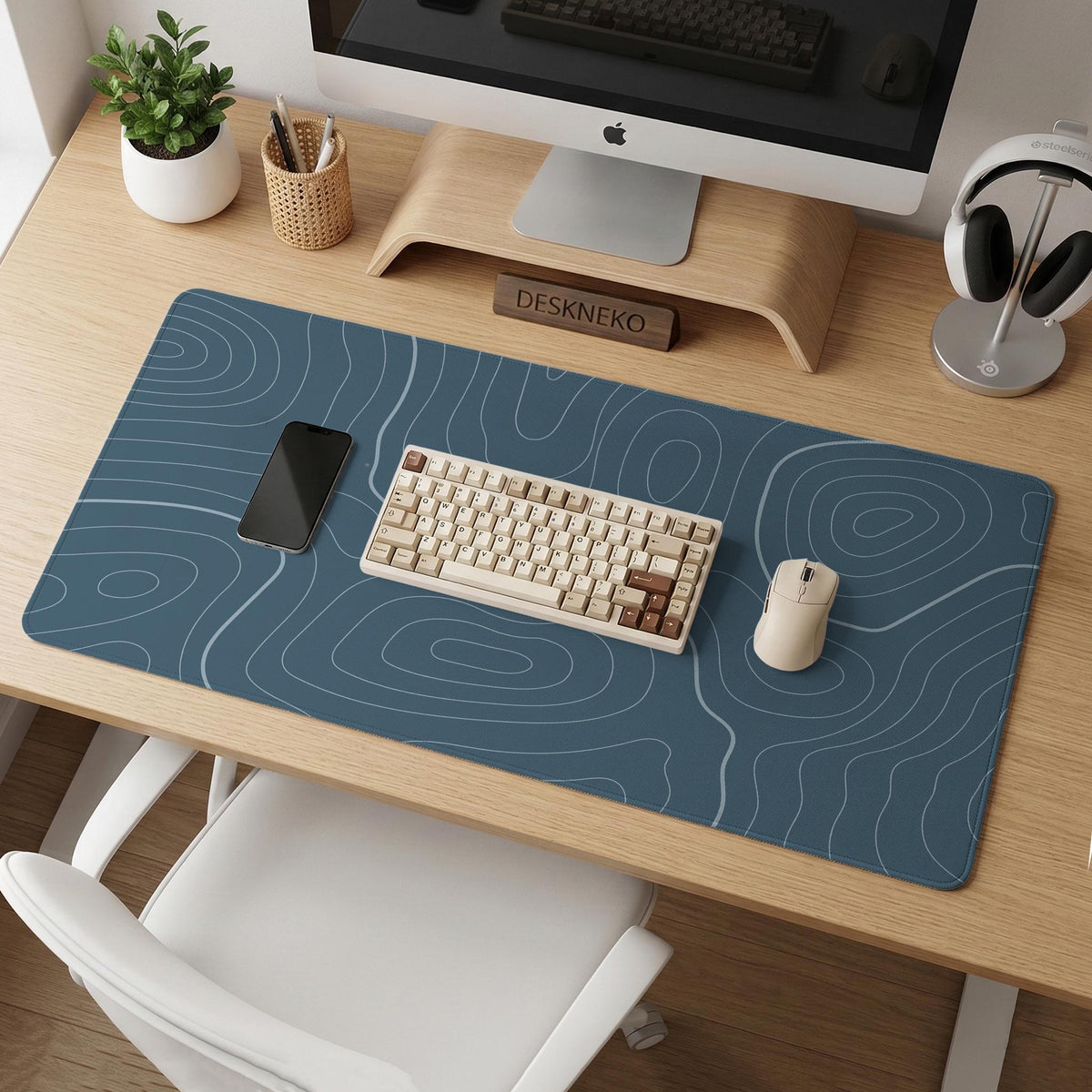 A slate blue desk mat with thin contour line map art on a light background.