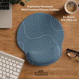 Muted blue desk mat with thin topographic line art pattern shown with matching mousepad and keyboard wrist rest options.