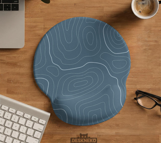Muted blue desk mat with thin topographic line art pattern shown with matching mousepad and keyboard wrist rest options.