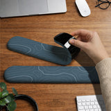 Muted blue desk mat with thin topographic line art pattern shown with matching mousepad and keyboard wrist rest options.