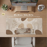 Beige desk mat with fine botanical line drawings and soft abstract shapes on a light neutral background.