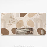 Beige desk mat with fine botanical line drawings and soft abstract shapes on a light neutral background.
