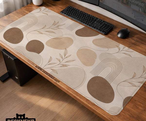Beige desk mat with fine botanical line drawings and soft abstract shapes on a light neutral background.