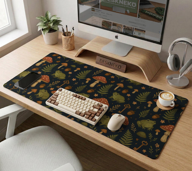 Dark forest-themed desk mat with an all-over pattern of frogs, mushrooms, fern leaves, acorns, tiny flowers, and antique keys.