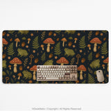 Dark forest-themed desk mat with an all-over pattern of frogs, mushrooms, fern leaves, acorns, tiny flowers, and antique keys.
