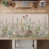 A desk mat with a botanical meadow design featuring wildflowers, leafy stems, and soft neutral colors.