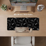 Black desk mat with a dark bat pattern and scattered stars on a charcoal background.