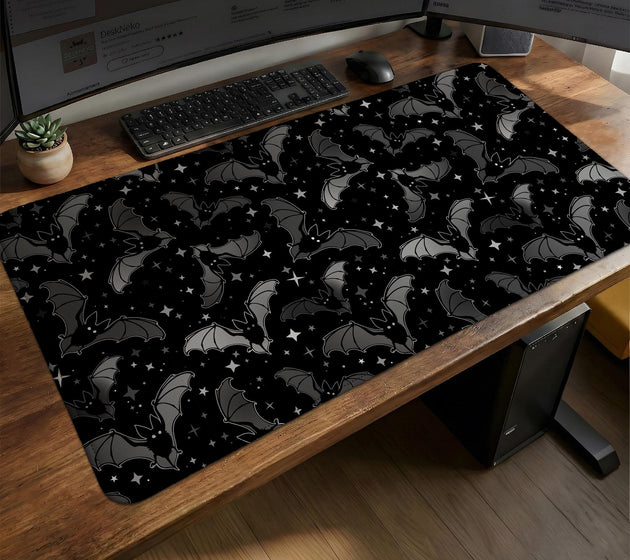 Black desk mat with a dark bat pattern and scattered stars on a charcoal background.