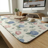 Floral desk mat with sage greenery, pink peonies, blue flowers, and a warm cream background.