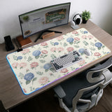 Floral desk mat with sage greenery, pink peonies, blue flowers, and a warm cream background.