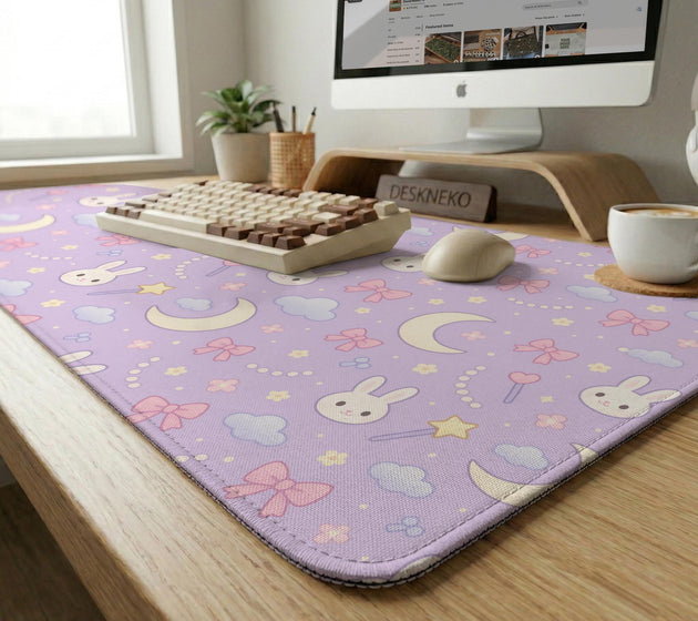 Lavender desk mat with an all-over pattern of bunny faces, clouds, moons, bows, and flowers in pastel colors.