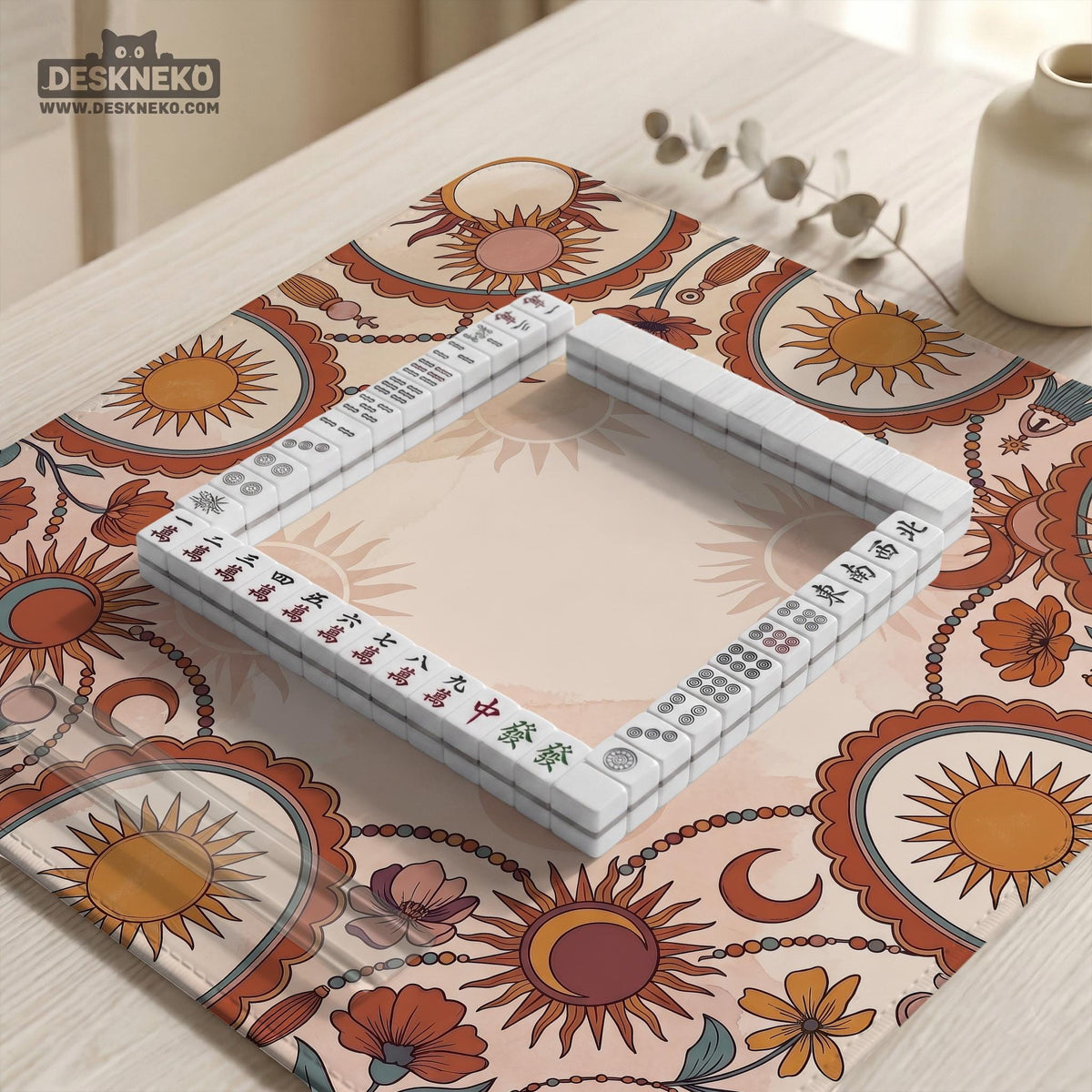 A square mahjong mat with a scalloped edge, sun and moon artwork, terracotta flowers, a soft cream background, and a decorative border around the play area.