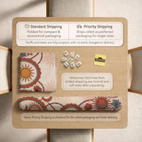 A square mahjong mat with a scalloped edge, sun and moon artwork, terracotta flowers, a soft cream background, and a decorative border around the play area.