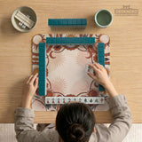A square mahjong mat with a scalloped edge, sun and moon artwork, terracotta flowers, a soft cream background, and a decorative border around the play area.