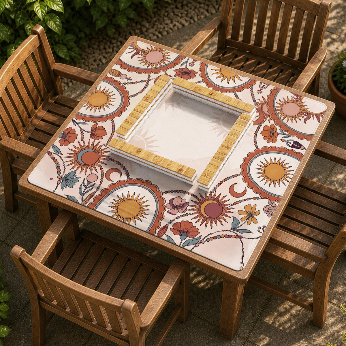 A square mahjong mat with a scalloped edge, sun and moon artwork, terracotta flowers, a soft cream background, and a decorative border around the play area.