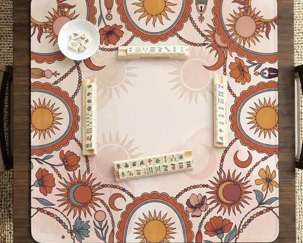 A square mahjong mat with a scalloped edge, sun and moon artwork, terracotta flowers, a soft cream background, and a decorative border around the play area.