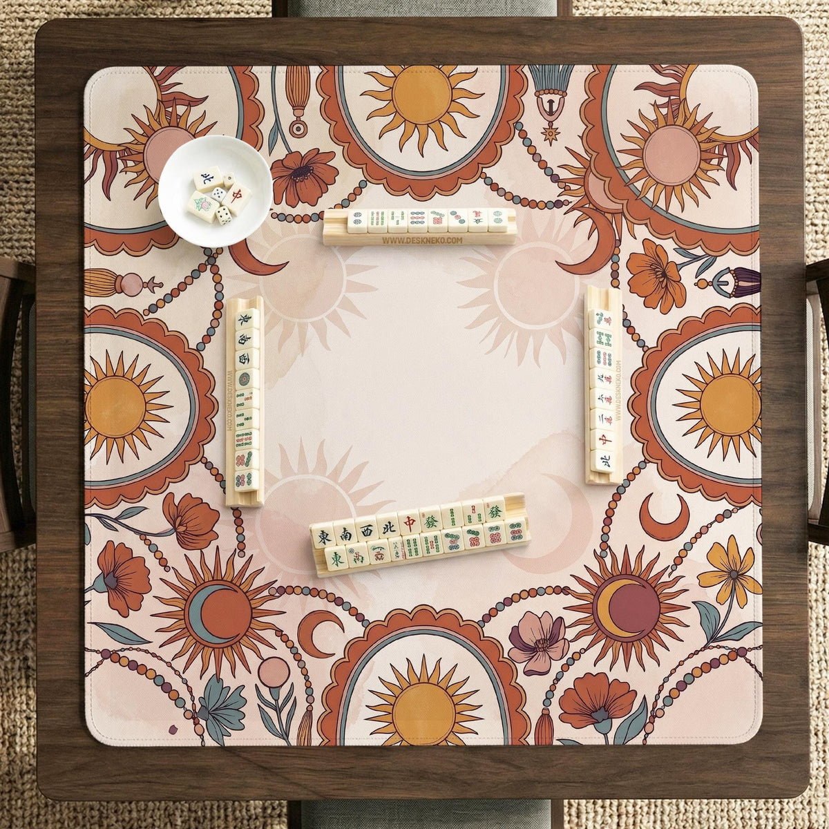 A square mahjong mat with a scalloped edge, sun and moon artwork, terracotta flowers, a soft cream background, and a decorative border around the play area.
