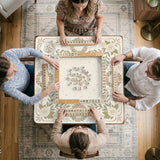 Square mahjong mat with a light floral border in sage green, cream, and blush around a plain center play area.