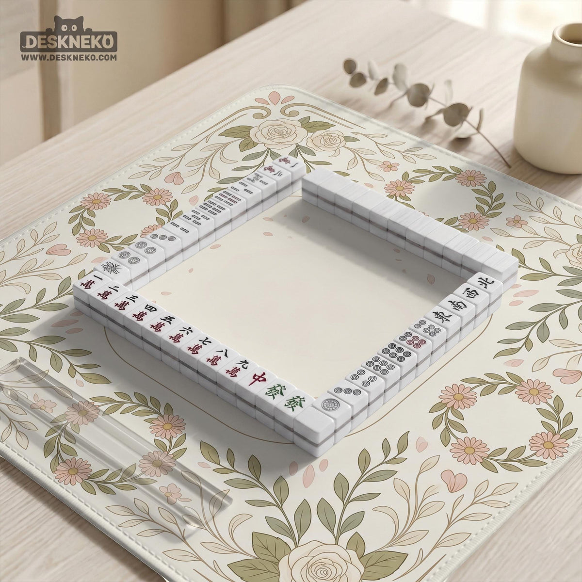 Square mahjong mat with a light floral border in sage green, cream, and blush around a plain center play area.