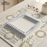 Square mahjong mat with a light floral border in sage green, cream, and blush around a plain center play area.
