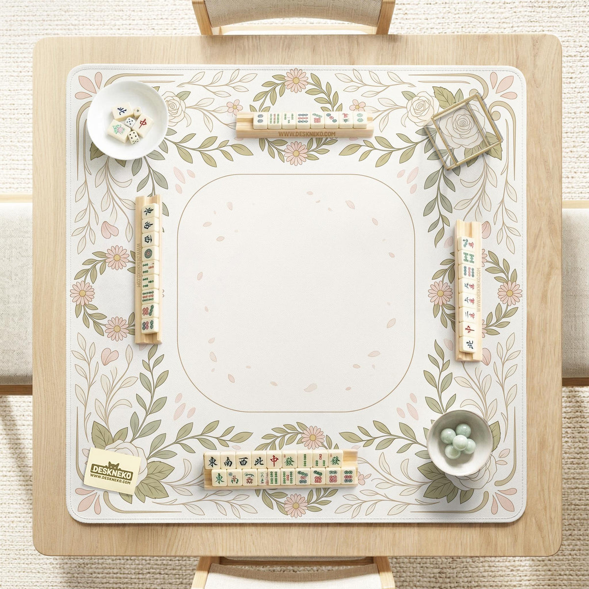 Square mahjong mat with a light floral border in sage green, cream, and blush around a plain center play area.