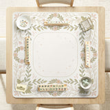 Square mahjong mat with a light floral border in sage green, cream, and blush around a plain center play area.