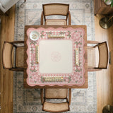 Square pink mahjong mat with a gingham border, floral corner details, and ribbon accents on a light background.