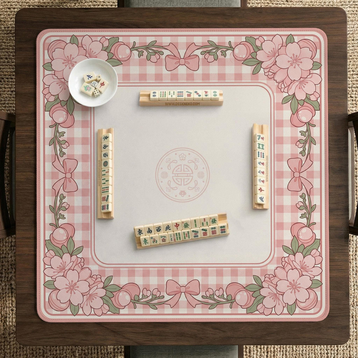 Pink gingham mahjong mat with a floral border, cherry blossom details, and a bow design around a plain center play area.