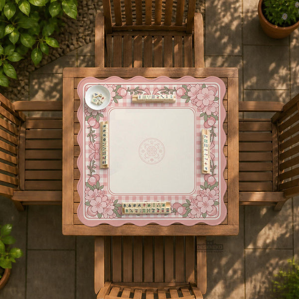 Pink gingham mahjong mat with a floral border, cherry blossom details, and a bow design around a plain center play area.