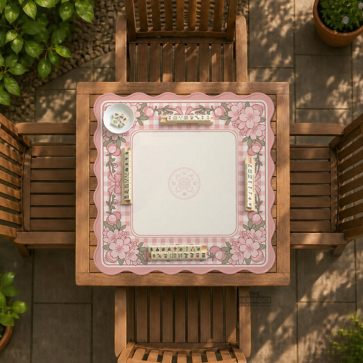 Pink gingham mahjong mat with a floral border, cherry blossom details, and a bow design around a plain center play area.