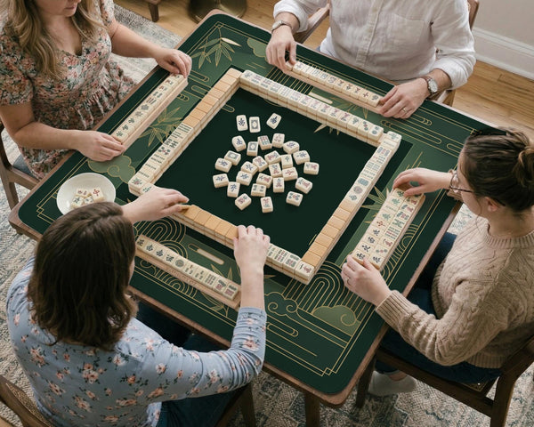 Square emerald green mahjong mat with bamboo line art, gold geometric cloud shapes, and a plain center playing area.