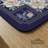 Blue mahjong table mat with a peacock and floral border, ivory center, lavender flowers, and scalloped edges.