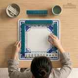 Square blue and white mahjong mat with peonies, cranes, pagoda accents, and chinoiserie linework around a plain center.