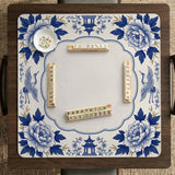 Blue and white mahjong mat with cranes, floral porcelain-style artwork, a cream center area, and a decorative border.