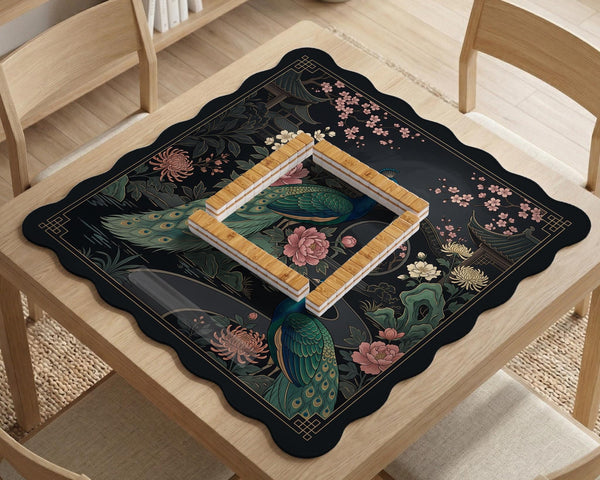 Square black mahjong mat with a gold peacock, blush flowers, and dark botanical artwork on a dark background.