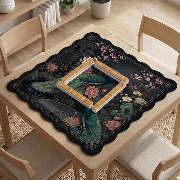 Square black mahjong mat with a gold peacock, blush flowers, and dark botanical artwork on a dark background.