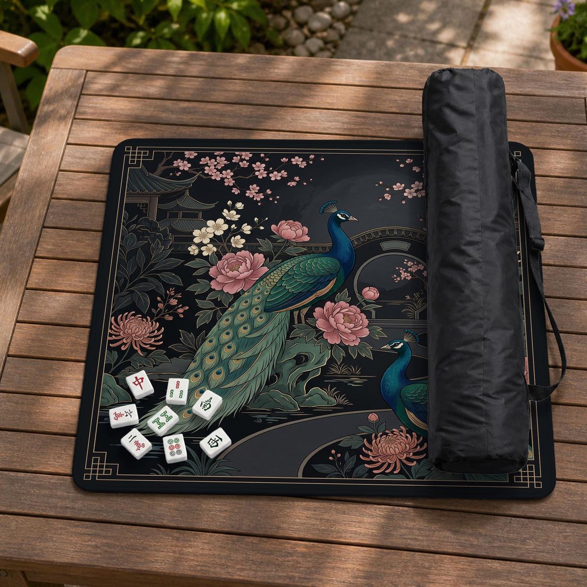 Square black mahjong mat with a gold peacock, blush flowers, and dark botanical artwork on a dark background.